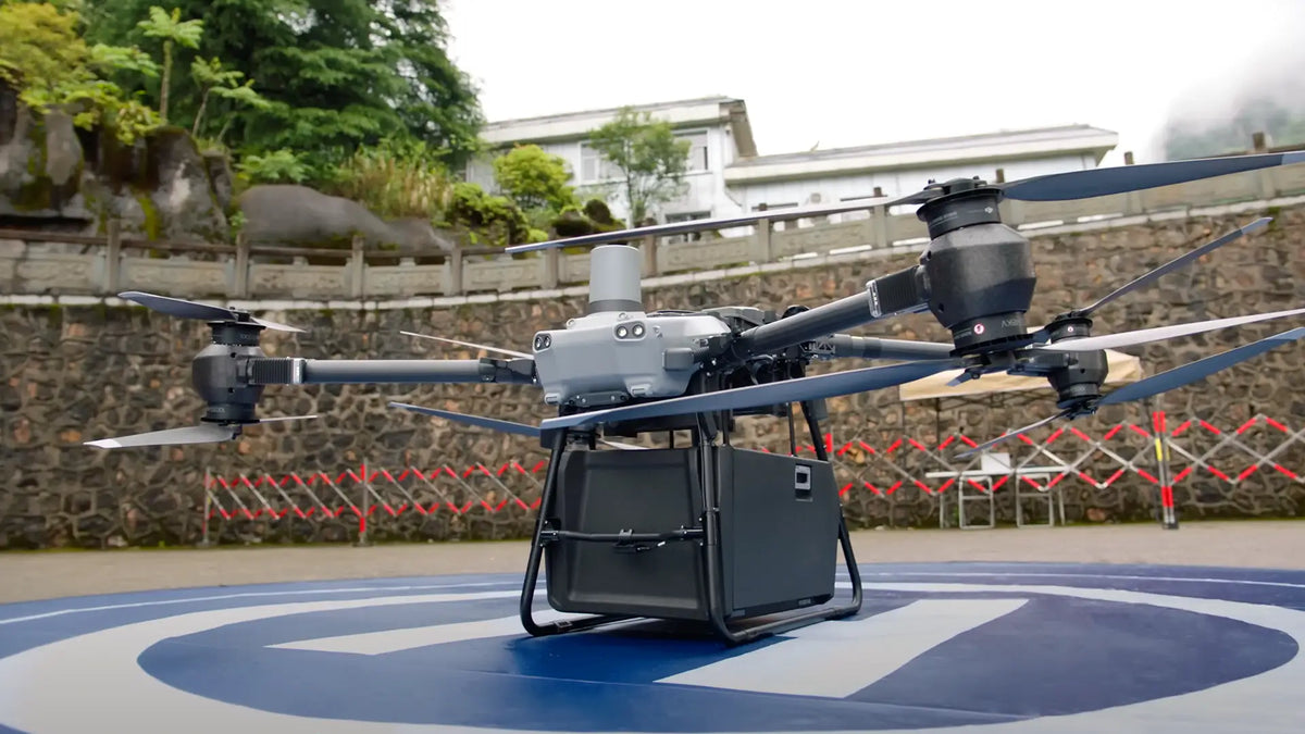 DJI FlyCart 30 delivery drone carrying a cargo box on a landing pad, showcasing heavy-lift aerial logistics for enterprise and commercial delivery operations.