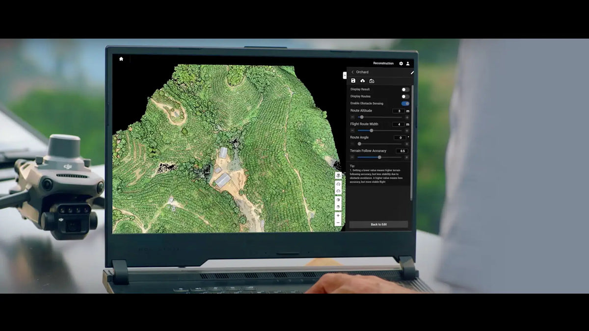 A laptop displays aerial terrain mapping software with an overhead view of green landscape. A drone is placed next to the laptop.