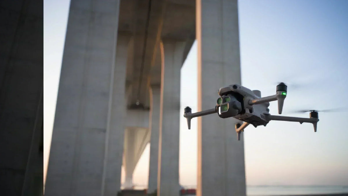 Drone performing bridge inspection with visible sensors during a wide-angle aerial shot, highlighting UAV use in infrastructure monitoring.