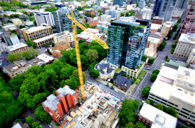 Aerial drone view of a large construction site with cranes and high-rise buildings, showcasing drone mapping, construction progress monitoring, site inspections, surveying, and project planning.