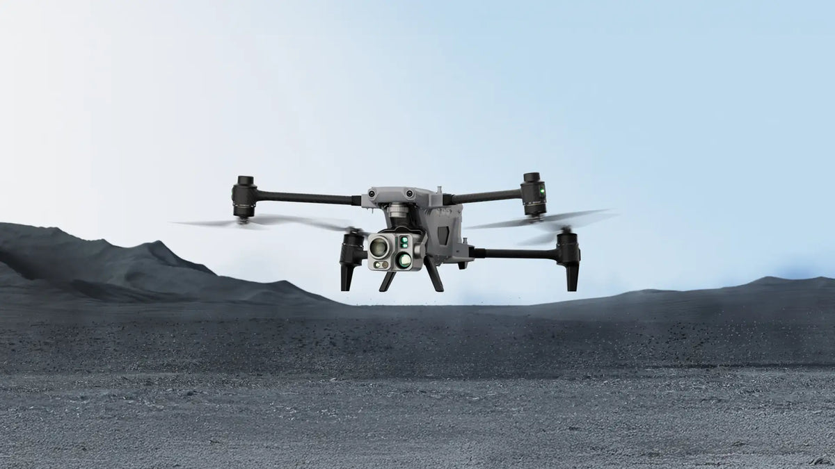 A sleek drone with four propellers hovers over a barren, rocky landscape against a clear blue sky, conveying a sense of advanced technology and exploration.