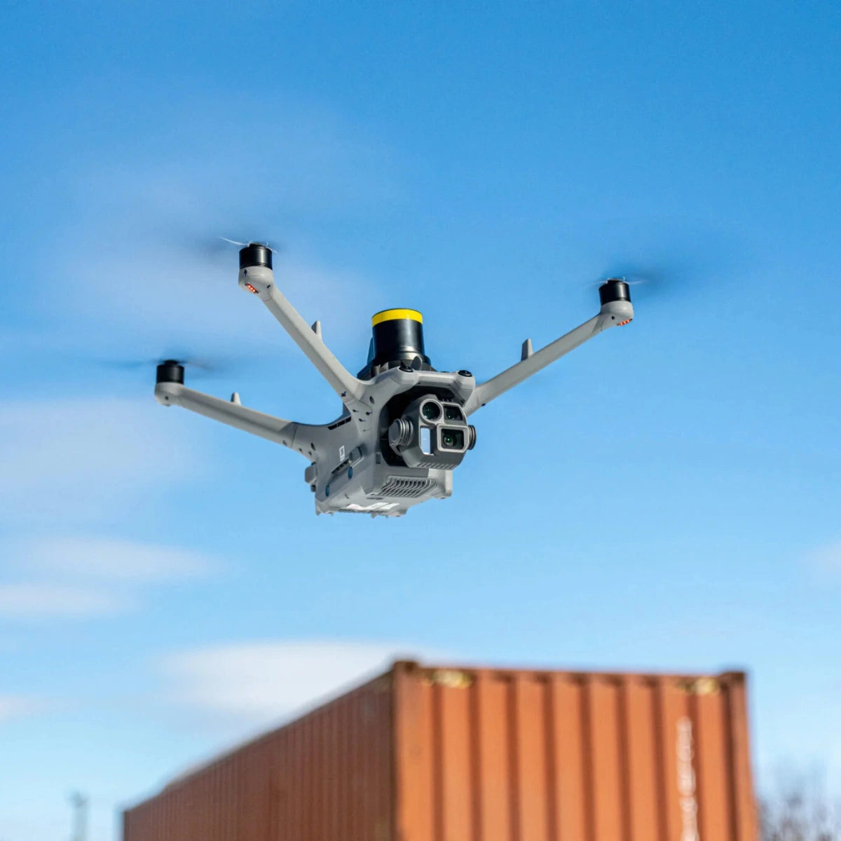 Matrice 4D Series drone with AVSS parachute recovery system flying above a shipping container